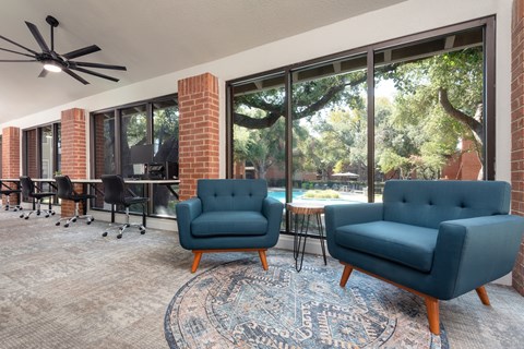 a living room with blue chairs and a rug and a large window